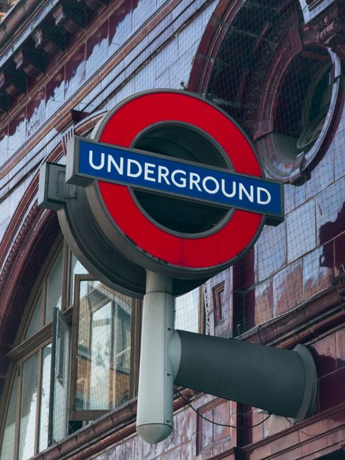 There is no image of flowers or floral arrangements provided; the image shows a close-up of a London Underground sign with a red circle and blue bar displaying 'UNDERGROUND' in white text, set against